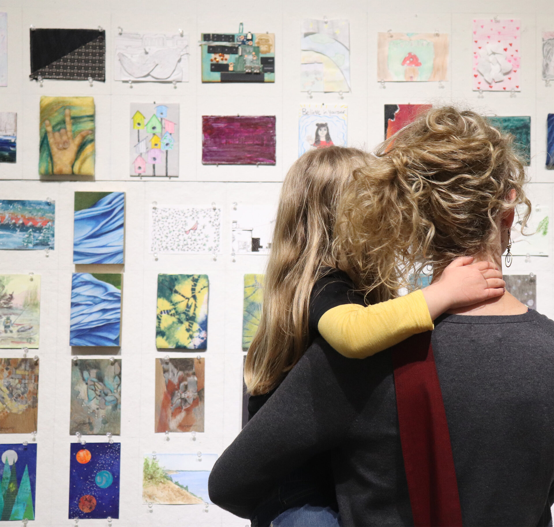 Mother and child looking at artwork hanging on a wall